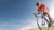 Man in red clothing riding a bike in the sunshine with blue clouds surrounding him