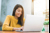 A woman in a yellow top reading her emails on a laptop