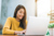 A woman in a yellow top reading her emails on a laptop