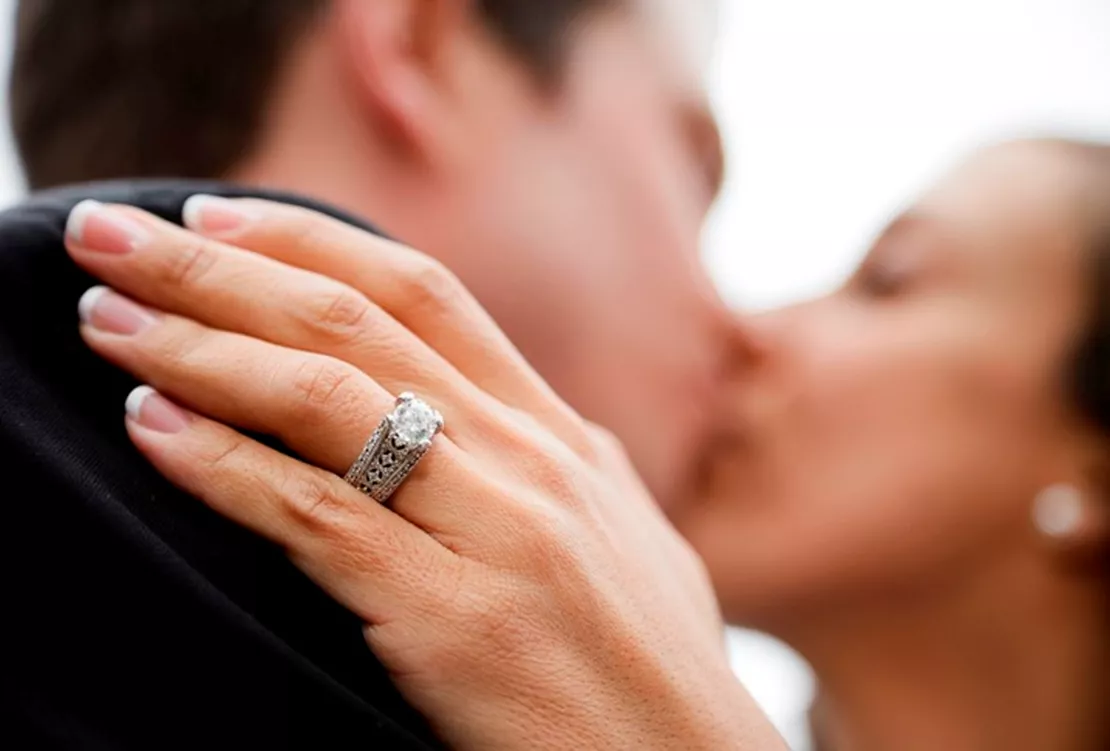 Man and woman kissing showing her engagement ring