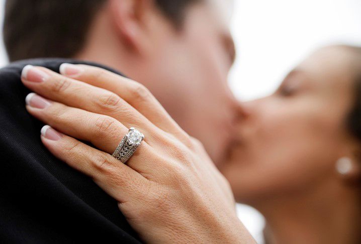 Man and woman kissing showing her engagement ring