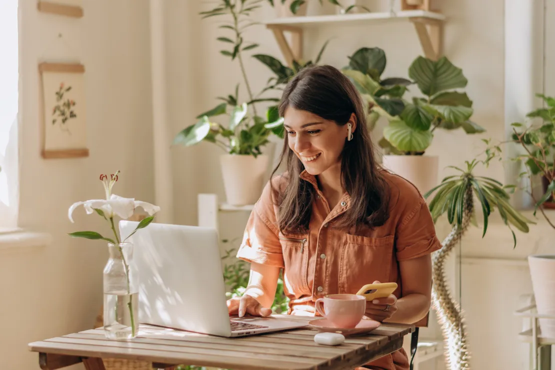 Positive Young Woman Using A Laptop And Smartphone At Home.