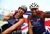 Two Great Britain wheelchair racers smiling and celebrating on the track, holding a Union Jack flag behind them after a race.