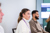 Employees sitting in a meeting, with a woman in a white sweater listening attentively in the foreground and colleagues seated beside her.