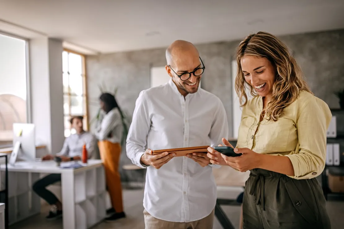 Businessman And Woman Smiling Looking At Phone