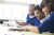 Three schoolchildren in blue jumpers studying in a classroom