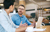 Two businesspeople talking over a coffee, looking at a laptop