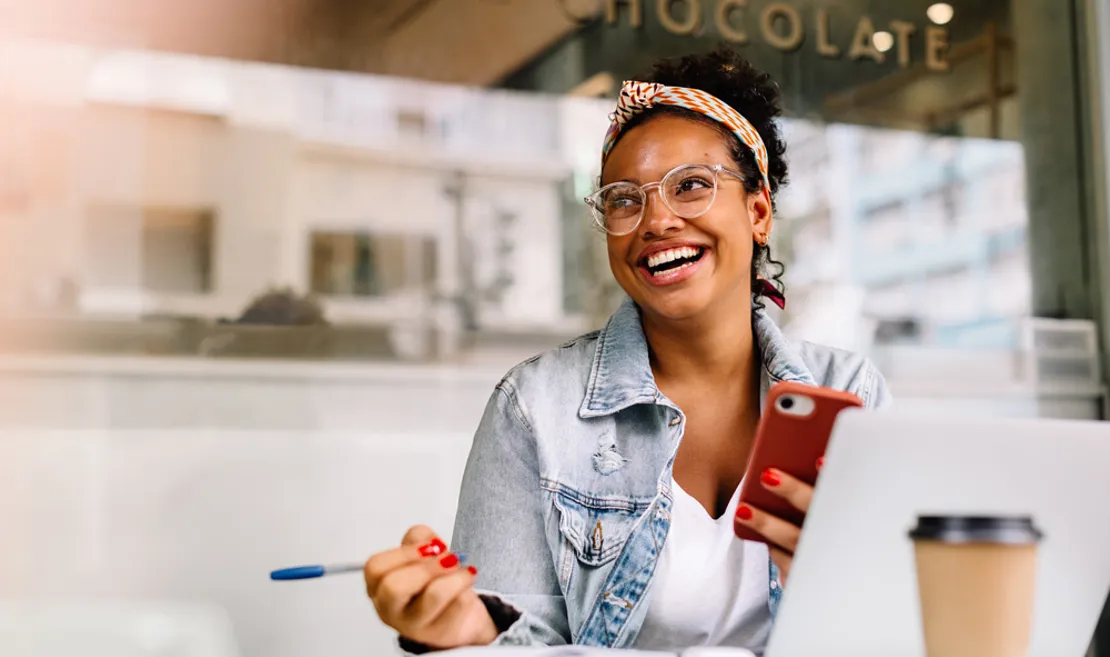 Woman Looking Into Distance Smiling Whilst Working On Laptop And Holding Pen (3)