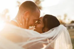Married couple embracing with veil wrapped around them