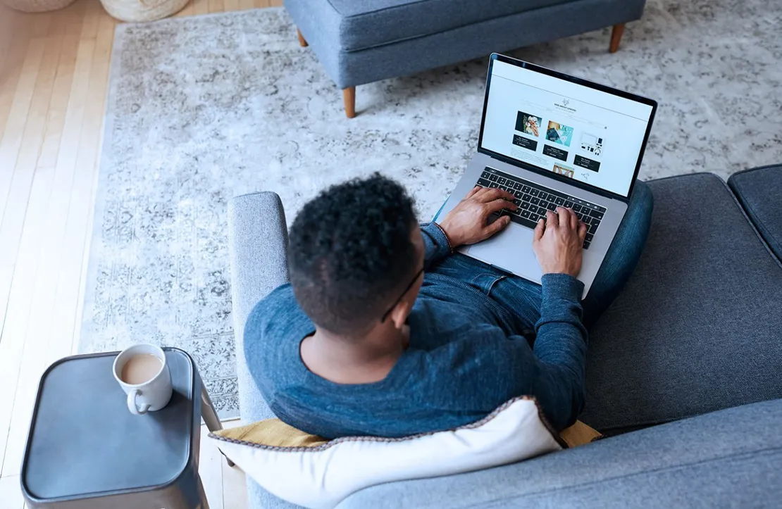 Man sitting on a sofa looking at a laptop