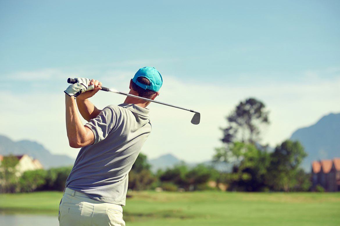 Man swinging a golf club on a golf course