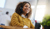 Customer service expert in a yellow jumper smiling while talking on her headset