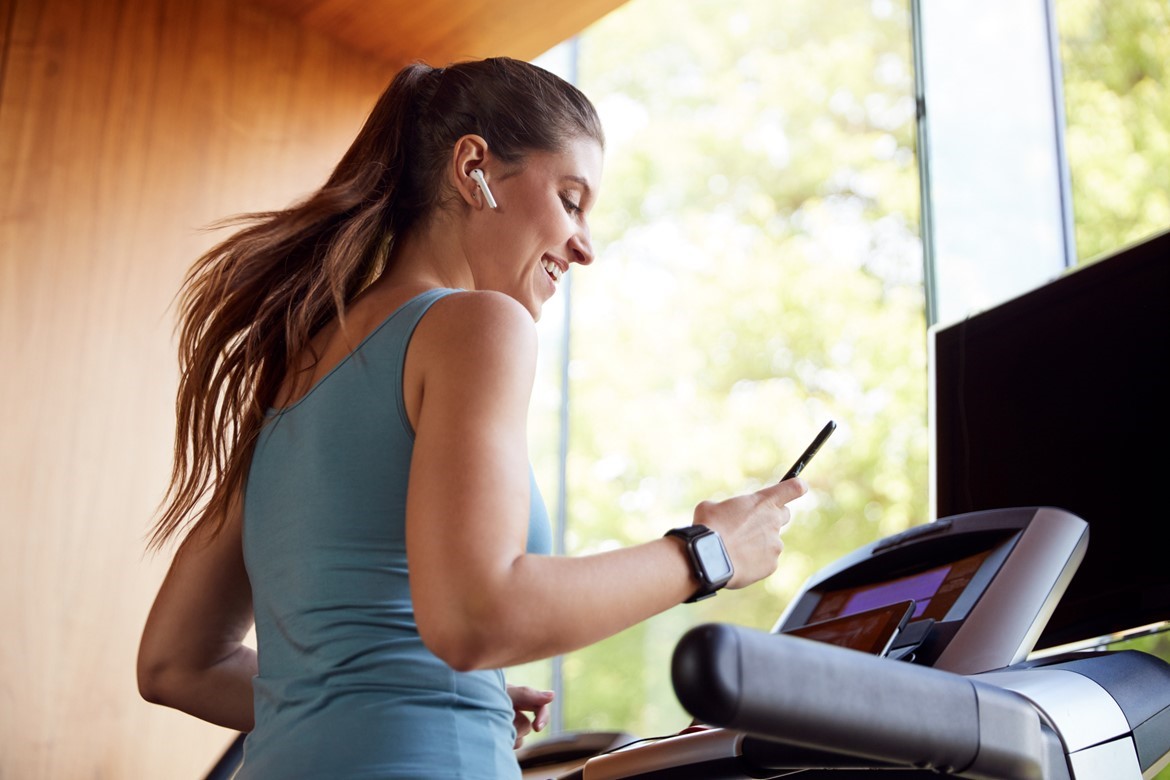 Woman looking at her phone while on a treadmill