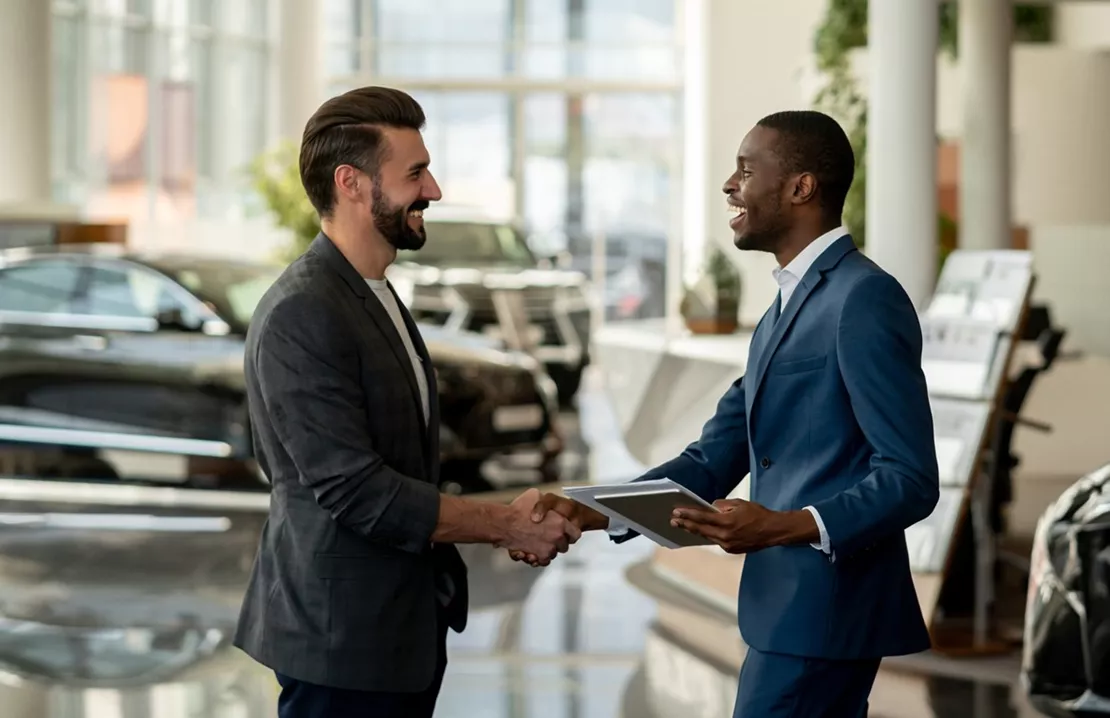 Two men shaking hands in a car dealership
