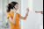 Woman in a yellow t-shirt inspecting her boiler while speaking to someone on the phone