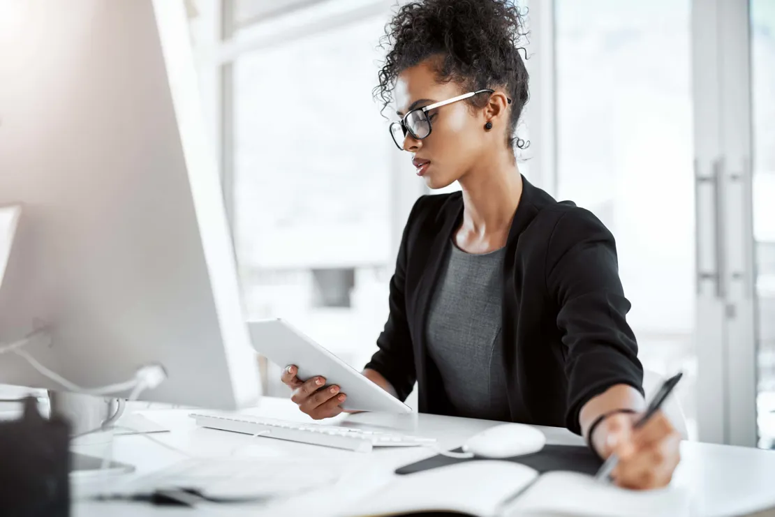 Woman taking notes while working on computer